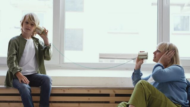 Mother and son play with tin can telephone
