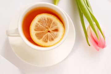 Pink tulip with a cup of tea on a light background, copy space. Postcard for seasonal holiday, spring concept, International Women's Day on March 8th