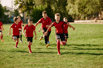 Full length portrait of children's soccer players team running on sport, football field on match in motion. Playing football. © Lustre Art Group 