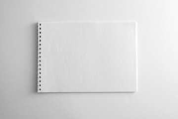 Mockup of white book, notebook, copybook, blank notepad cover with metal spiral template on white...