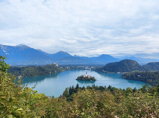 Fototapeta na wymiar view to the island on lake Bled and dark blue mountains. Slovenia under white clouds