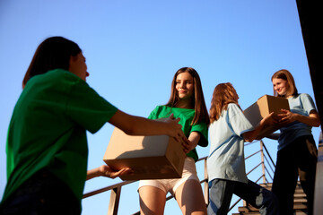 Volunteers standing on stairs with boxes filled with humanitarian help, clothes, goods, food and meds for people and animals in need. Humanitarian aid, assistance and support, social programs concept