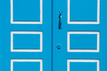 Blue-painted vintage wooden door with metal handle close up.