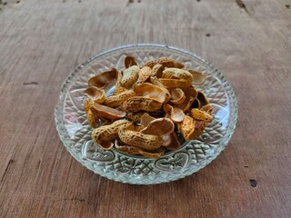 pile of shelled peanuts on plate isolated on wooden background