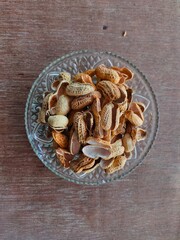 pile of shelled peanuts on plate isolated on wooden background