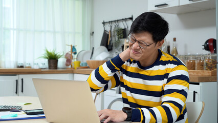 asian business man using laptop Suffering From neck pain working at home office syndrome . Asia male teacher teaching online on desk . education at home . - obrazy, fototapety, plakaty