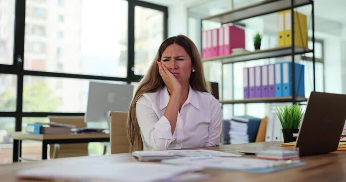 Woman struggles suffering from toothache during work day in office. Businesswoman thinks about visiting dentist after work slow motion