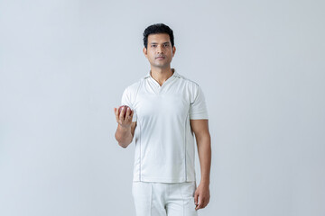Portrait of Cricketer holding cricket boll in hand and looking towards the camera in aggression ,...