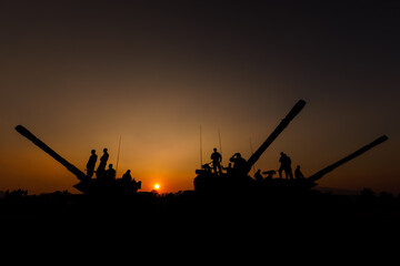 silhouette group of special forces sodiers standing and sit on tank with over the sunset background,.
