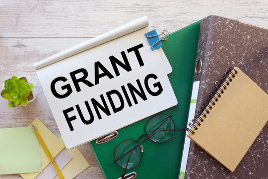 Grant funding symbol. Copy space. work desk glasses and sticker. notepad with text on a folder.