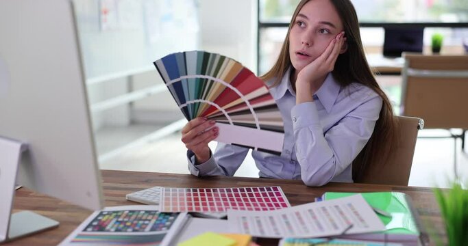 Office worker creates paper fan from paint colour sheets. Employee in blouse waits for client to arrive to meeting about house renovation slow motion