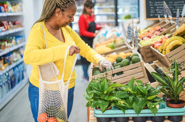 African female customer buying organic food fruits inside minimarket - Small business and healthy...