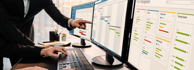 Project management team coordinating and update project planned schedule on computer using Gantt...