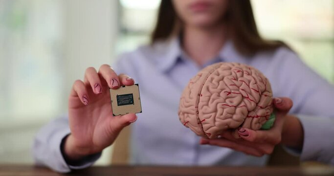 Woman holds artificial model of brain and computer motherboard in lit office. Concept of unity of brain and computer technologies for university slow motion