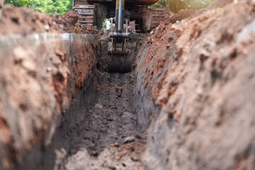 Backhoe digging dirt to make drainage pipes      