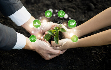 Businessman and little kid growing or nurturing plant together on fertile soil with eco friendly...