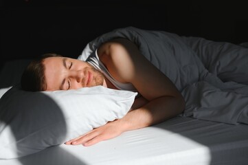 Handsome man sleeping under soft blanket in bed at home, above view
