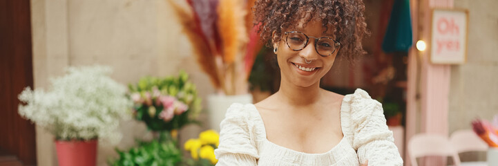 Young woman in glasses looks at bouquets of flowers in a flower shop.