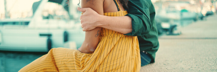 Close-up, a man hugs a woman and strokes her hand. Closeup of happy interracial couple are sitting...