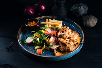 Chicken medallions fillet with French fries and fresh vegetable salad.