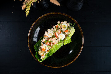 Salad Olivier from boiled vegetables, eggs, sausage, red caviar, greens and mayonnaise.