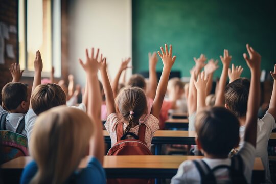 Children raise their hands to answer in the classroom