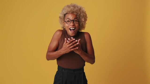 Young woman ooking at camera in a pleasant joyful surprise isolated on orange background
