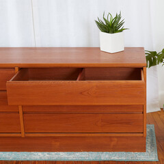 Sleek teak dresser. Vintage 1970s style furniture. Close-up detail with open drawer and houseplant....