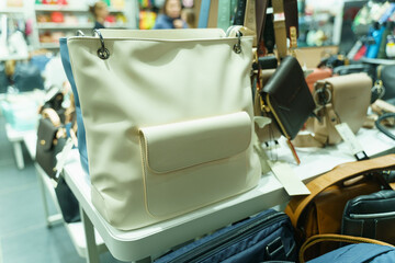 A shop window selling bags, with a white leather women's bag in the foreground.