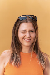 Portrait of a woman with sunglasses on her head winking an eye and smiling.