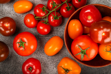 Tomatoes on marble texture background. Cherry tomatoes, yellow, pink, brown and black tomatoes in a bowl. Organic vegetables, harvesting.Vegan. Fresh ripe tomatoes. copy space.