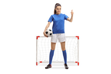Full length portrait of a female soccer player making a thumb up sign in front of a mini goal