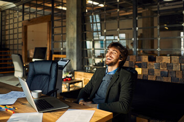 Young Caucasian male designer is happy with how his work turned out in a startup company office