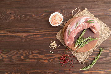 Raw pork with herbs and spices on a brown wooden. Top view, copy space.