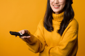 Close up of a content young Asian woman in her 20s, dressed in a yellow sweater, enjoying her...