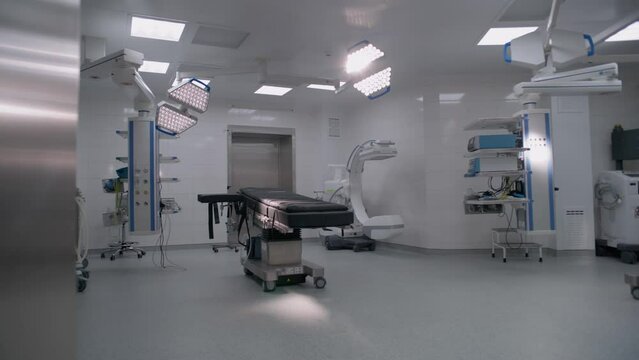 Dolly shot of operating room in modern hospital with advanced equipment for surgery. Operating table, LED lamps, life support and anesthesia machine. Operation block in clinic or medical facility.