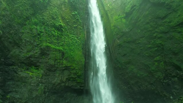 Beautiful rain forest foggy waterfall. Kabut Pelangi air terjun in Lumajang, East Java Timur. Aerial dramatic drone view.