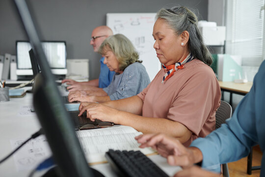 Mature Asian woman attending computer training class to learn basic skills