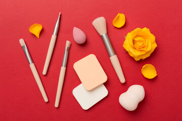 Makeup brushes and sponges on color background, top view