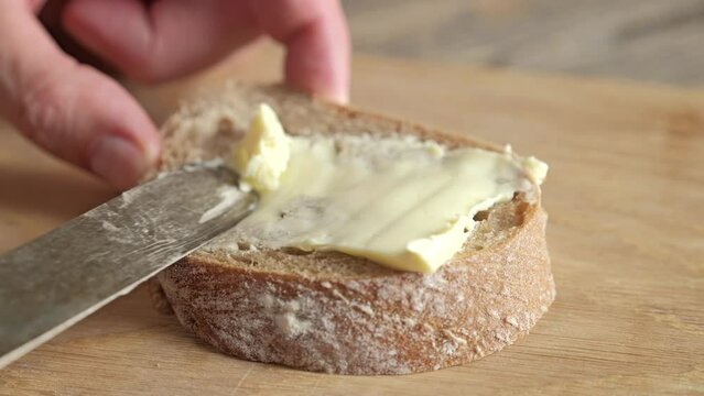 Close-up of spreading butter on ciabatta bread with a vintage knife.