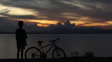 silhouette of a bicycle against the background of the sunset on the lake
