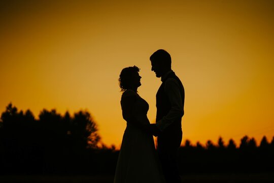 Silhouette of the newlyweds at sunset - is a picturesque scene often captured in wedding photography
