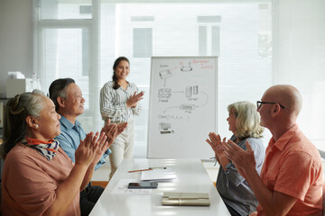 Group of senior people and teacher clapping after finishing lesson on wireless internet