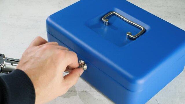 Man Hand puts a gun revolver pistol into the metal safe box. Lock Box with Key Closing. Passport, mobile and cash in safe with kay.