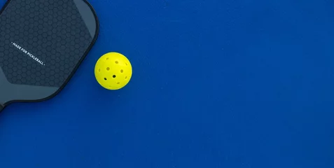 Pickleball tennis racket on the court. Blue background with copy space. Sport court and ball. © Mike Orlov