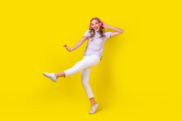 Fototapeta na wymiar Full size photo of good mood nice girl wear violet polo white trousers having fun listen playlist isolated on yellow color background