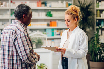 Fototapeta premium Woman pharmacist talking with a senior patient customer in a pharmacy