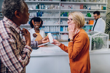 Diverse senior couple buying drugs in a pharmacy while standing next to counter