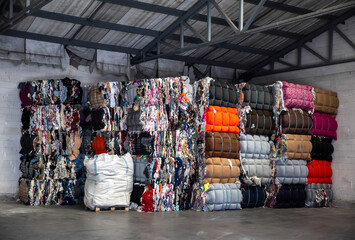 Heap of pressed colorful textile waste packed in bales in store-house - obrazy, fototapety, plakaty
