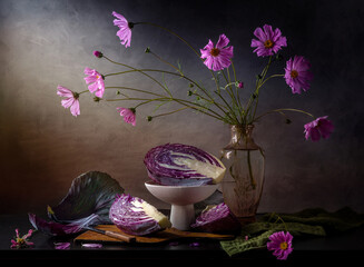 Modern still life with cut red cabbage and pink flowers in a vase on a dark table